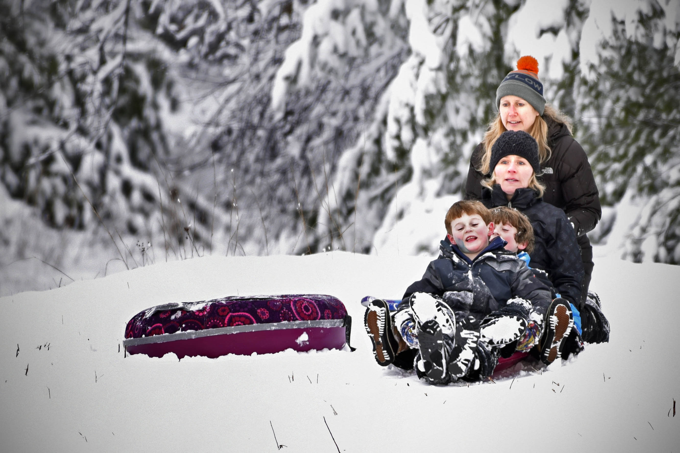 Mother pushing children on their snow sled